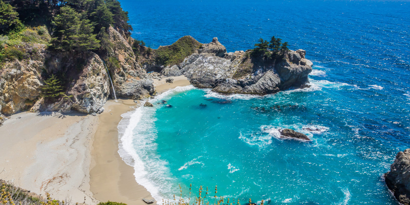 turquoise water rushes onto a rugged beach