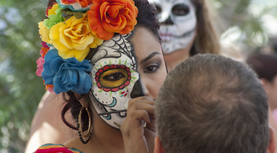 Woman paints person's face at Day of the Dead event at Mesa Art Center in Arizona