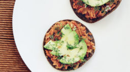 A pair of trout tostadas topped with slices of avocado