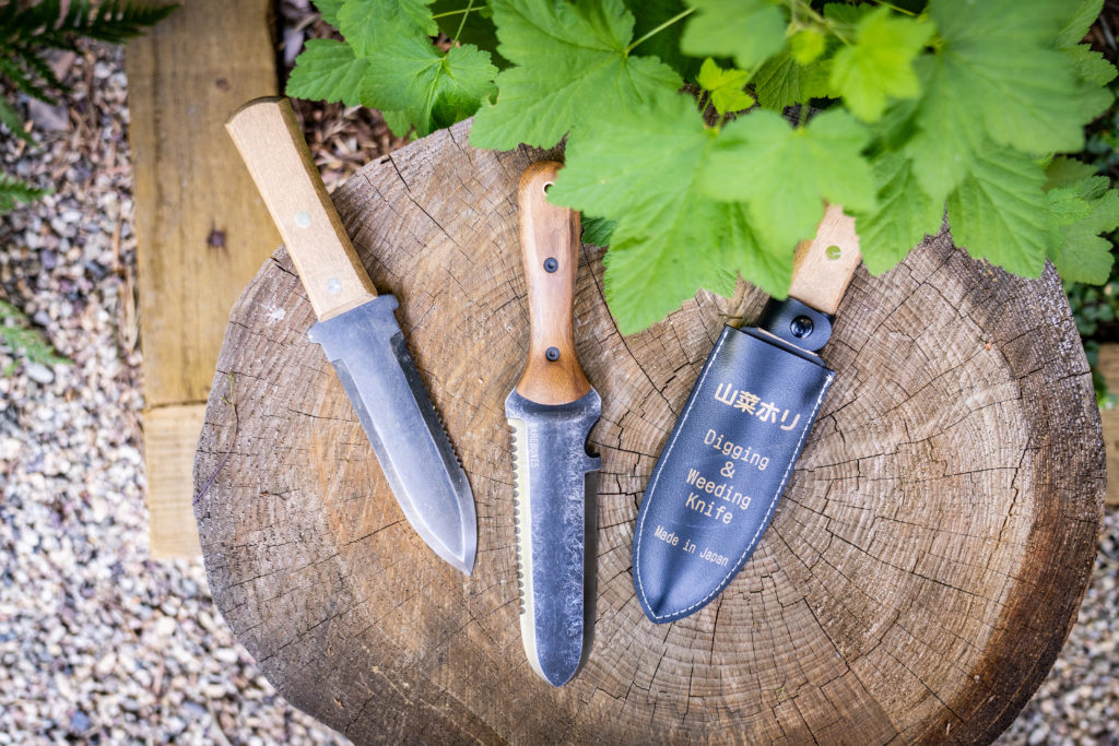 Three HoriHori garden knives on a tree stump