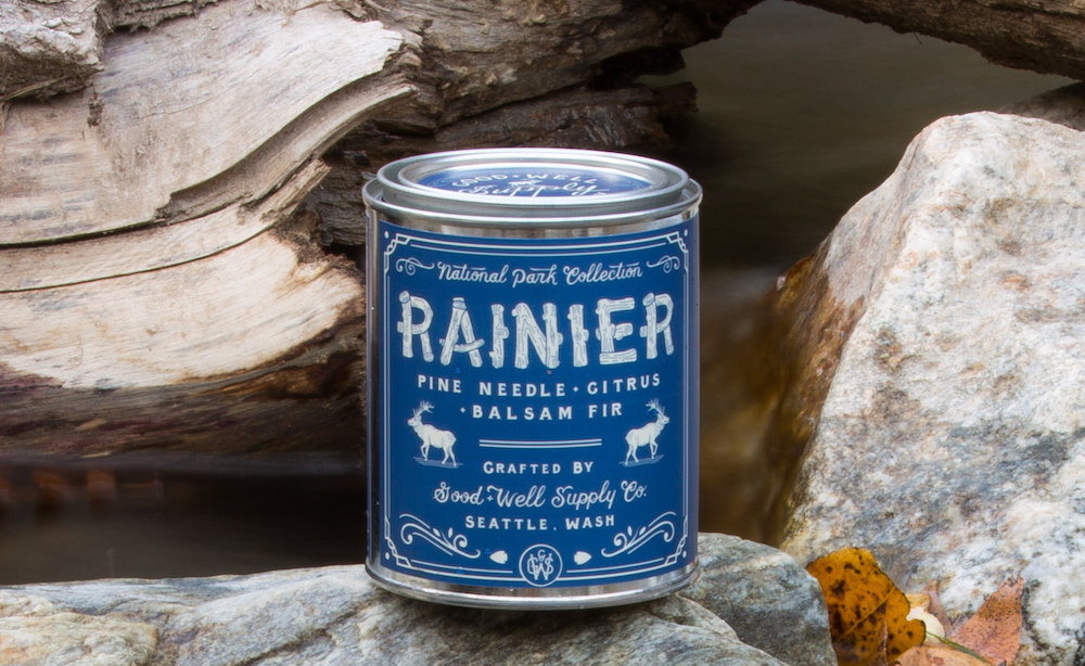 candle in blue tin can sitting on rocks and logs