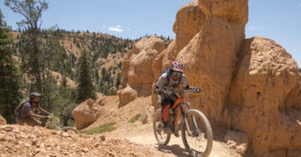 mountain bikers riding through off-road terrain among red rocks and trees