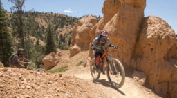 mountain bikers riding through off-road terrain among red rocks and trees