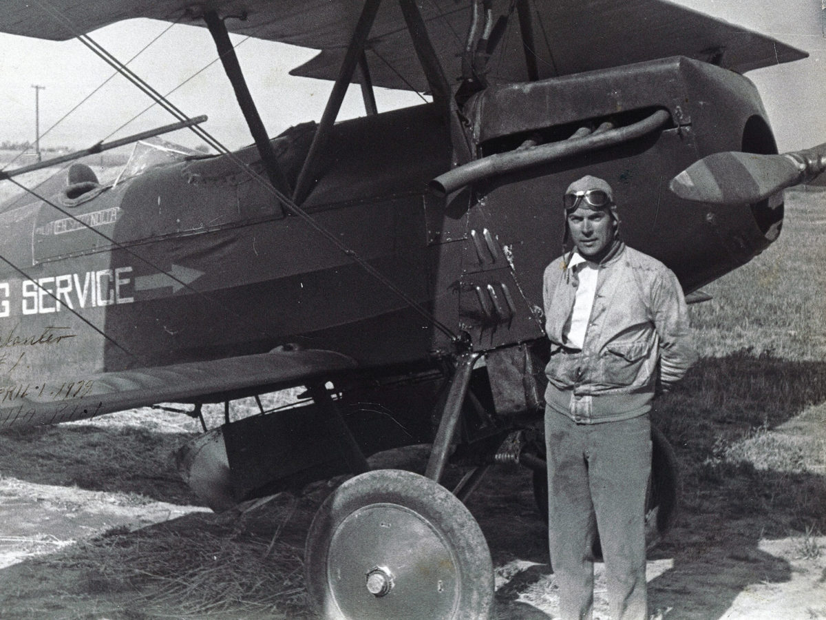 Floyd Nolta stands alongside a biplane