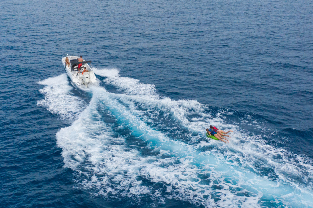 People on raft are pulled by a boat in the ocean