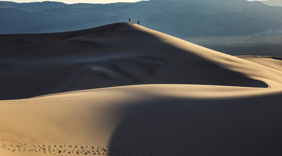 Two hikers atop a giant sand dune in Death Valley