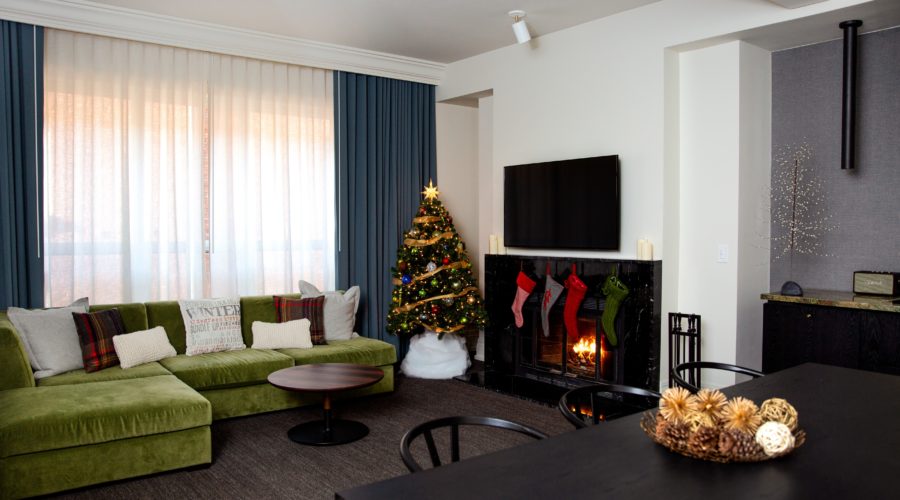 A suite inside the Kimpton Alexis Hotel decorated for the holidays with a Christmas tree and stocking around the fireplace