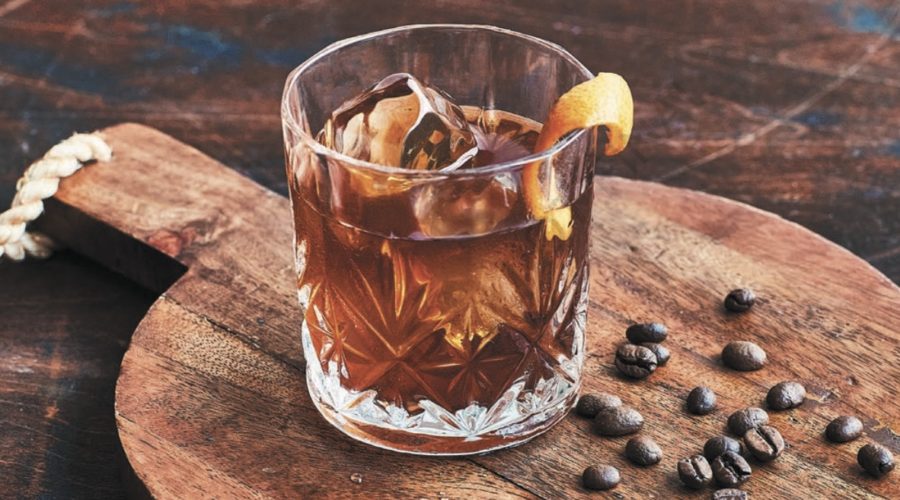 coffee old fashioned by coffee beans on wooden serving paddle