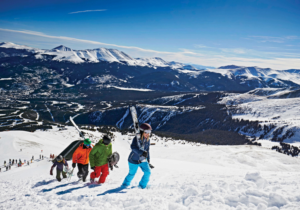 Family climbing up a ski hill on a blue bird day in Breckenridge