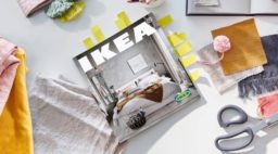 Copy of IKEA 2021 catalog book on table with multicolored fabrics and scissors as background.