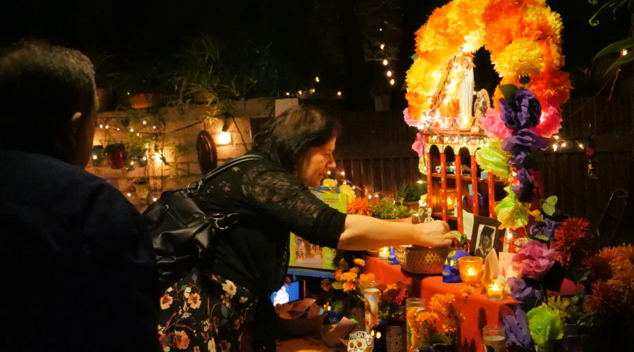 Woman placing an ofrenda (offering) on the altar during a Day of the Dead event in Tucson