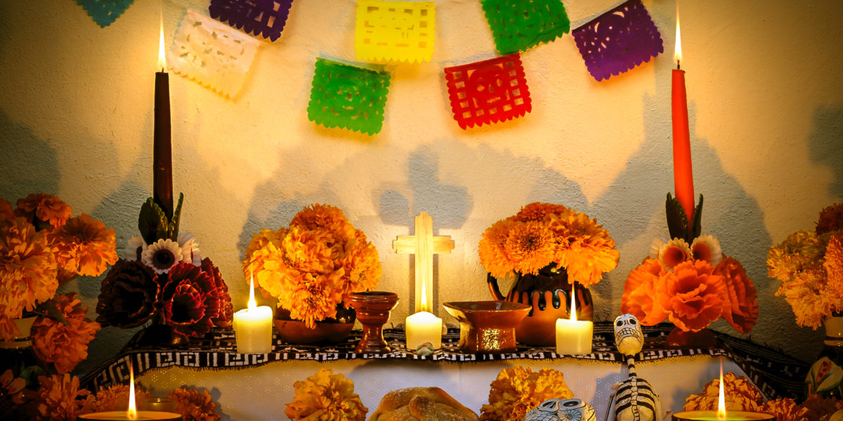 Traditional mexican Day of the dead altar with cempasuchil flowers, bread "pan de muerto", "papel picado" ornaments and candles.