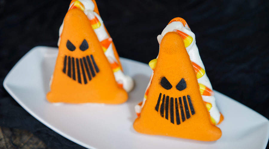 A traffic cone-shapped macaron with candy corn and buttercream filling
