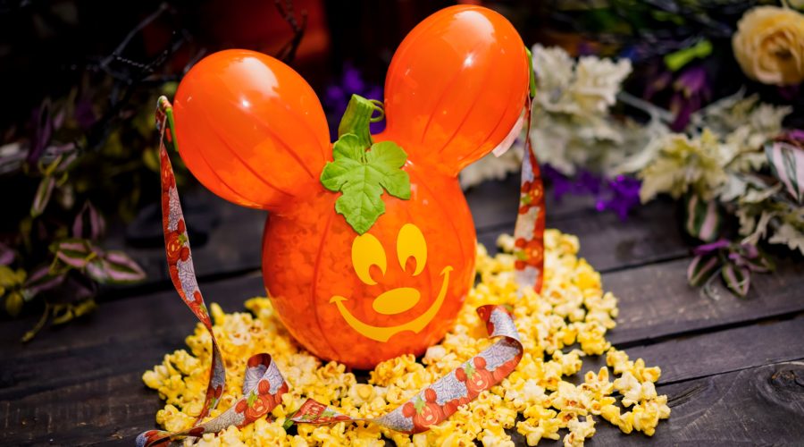 An orange popcorn bucket in the shape of mickey mouse, looks like a jack-o-lantern