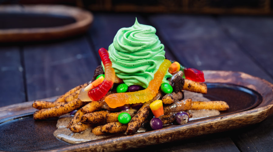 pile of funnel cake fries with green whipped topping and gummy worms