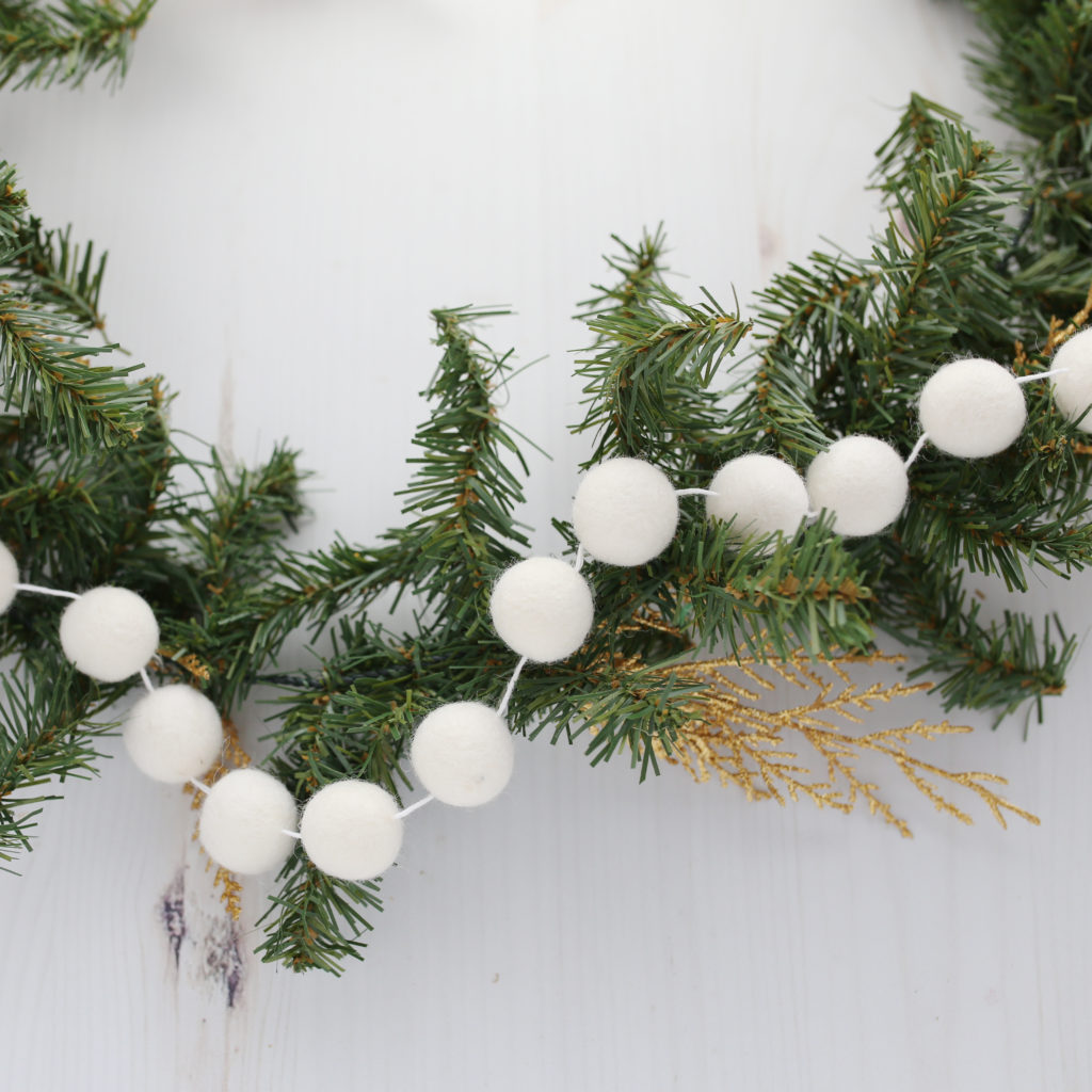 felt ball garland strung among pine garland