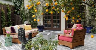 An orange tree hangs over two square, raw concrete fire pits