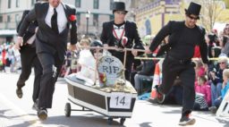 Men in pallbearer costumes racing with a fake coffin in the Emma Crawford Halloween events in Manitou Springs, CO