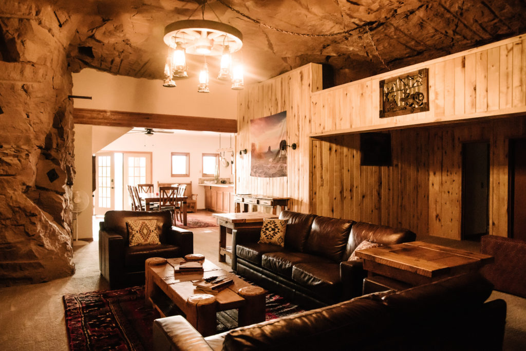 leather couches and wood coffee table inside living room with cave walls and ceiling