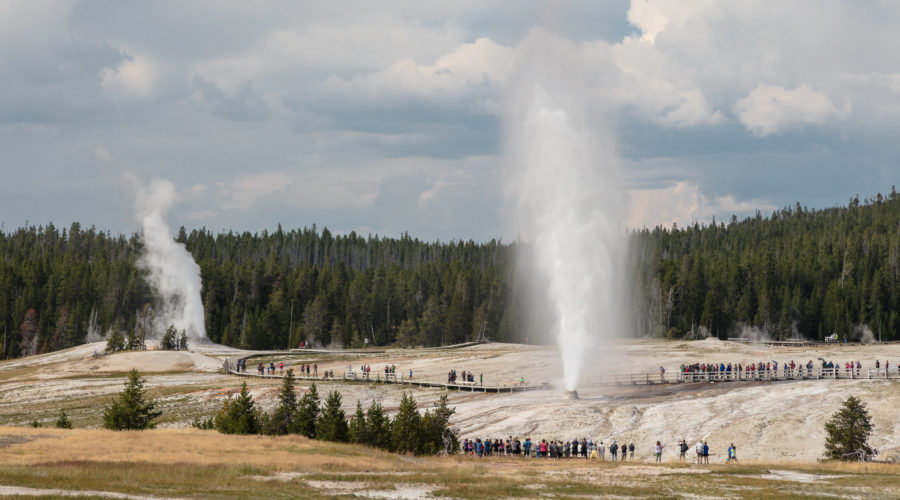 People watching Beehive Geyser erupt with Lion Geyser in Yellowstone off Highway 89