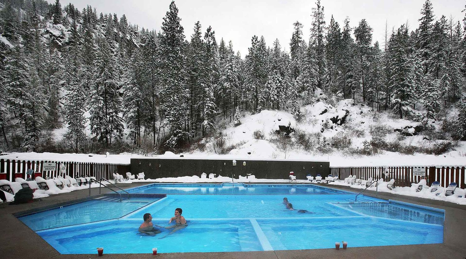 People soaking in the pool at Quinns with snow-covered trees in the background