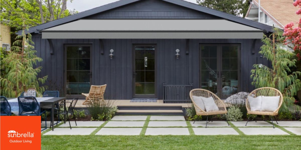 Farmhouse shown with Crest Ash (4662) Sunbrella awning with black frame on a dark blue house created with Sunbrella Shade Studio.