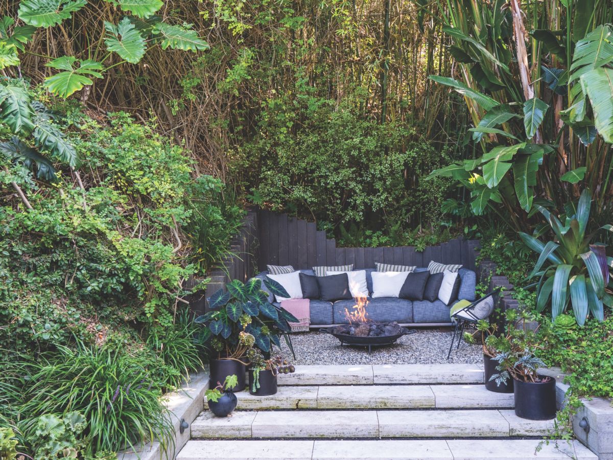 Shallow stairs lead to an elevated nook with a generous sofa and vintage firepit.