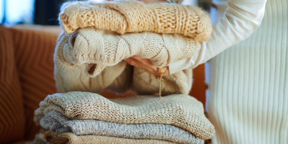 A close-up of a person stacking sweaters.