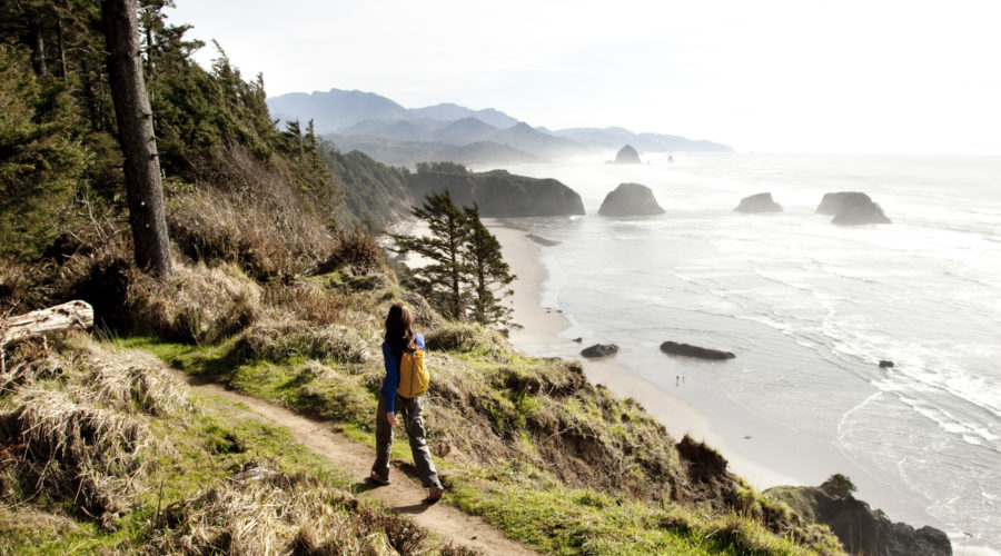 A woman hiking a path near the Oregon Coast with a Pacific Northwest trip
