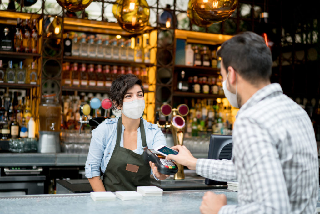 bartender wearing a mask taking payment