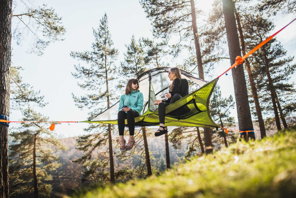 two people sit in a tree tent off the ground