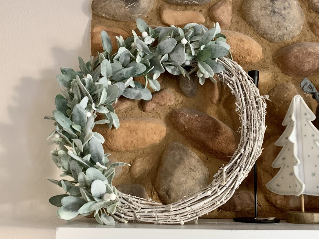 wreath with white branches and green leaves on mantle