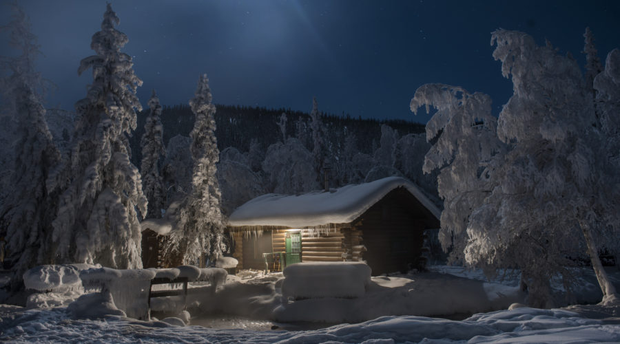 Chena Hot Springs by snow covered trees against log cabin