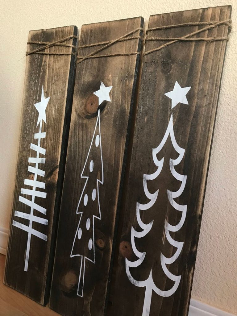 three wooden planks wrapped in twine with different white trees painted on