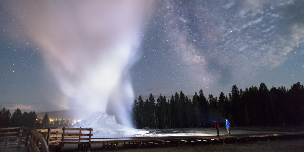 Father and son watch a Castle Geyser night eruption at Yellowstone National Park, one of the things you must see in Yellowstone