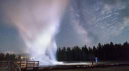 Father and son watch a Castle Geyser night eruption at Yellowstone National Park, one of the things you must see in Yellowstone